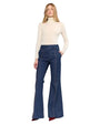 A woman is dressed in a turtleneck sweater and wide-leg denim pants, presenting a chic and relaxed fashion look.
