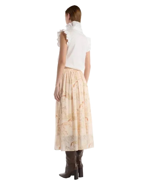 Back view of a woman in a white blouse and a long skirt that is decorated with a charming design of horses.