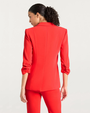 Back view of a person in a bright red suit with matching pants, standing against a plain white background.