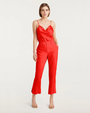 Woman wearing a red sleeveless top and red pants against a neutral background. 