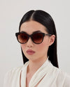 A model wearing stylish sunglasses with brown lenses, showcasing a trendy summer look.
