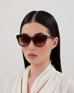 A model wearing stylish sunglasses with brown lenses, showcasing a trendy summer look.

