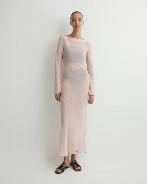 Blush pink sheer long-sleeve maxi dress with a semi-transparent design and fitted silhouette