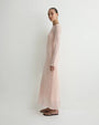 Side view of a blush pink sheer long-sleeve maxi dress with a fitted silhouette and flowing hem