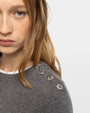 Close-up of gray knit sweater with silver star embellishments on shoulder