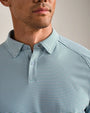 Close-up of a light blue striped performance polo shirt featuring a classic collar, two-button placket, and fine horizontal stripe pattern.