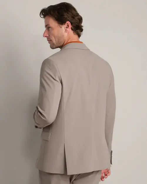 Back view of a men's taupe tailored blazer worn with matching trousers, showcasing the clean silhouette and center back vent.
