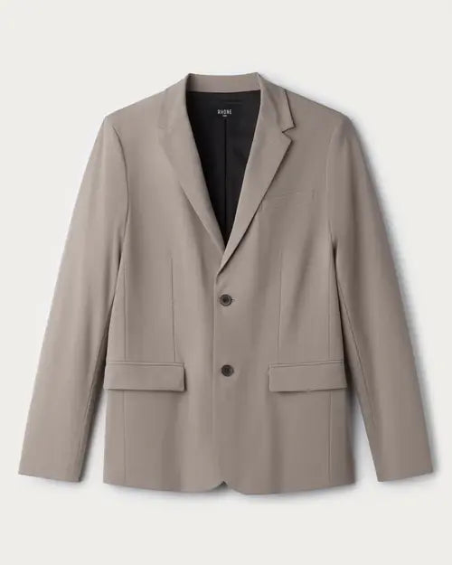 Men's taupe tailored blazer with notch lapel, two-button front closure and flap pockets on a light neutral background.