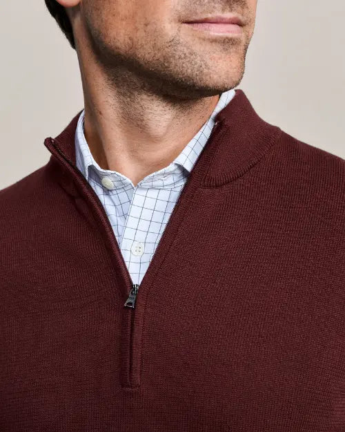 Close-up of a men's burgundy mock neck quarter-zip knit sweater with ribbed texture and zipper placket