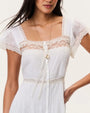 White maxi dress with lace trim detailing, flutter sleeves, button-front design, and a tiered skirt, styled on a neutral studio background.