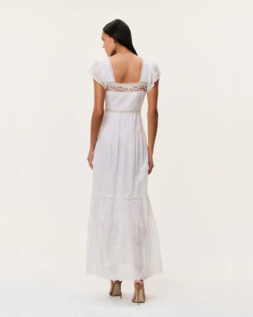 Back view of a white lace-trim maxi dress featuring a square open back, flutter sleeves, fitted waist, and flowing tiered skirt.