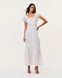 White maxi dress with lace trim detailing, flutter sleeves, button-front design, and a tiered skirt, styled on a neutral studio background.
