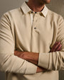 Close-up of a men's beige long-sleeve polo shirt featuring a classic collar, three-button placket, and ribbed cuffs.