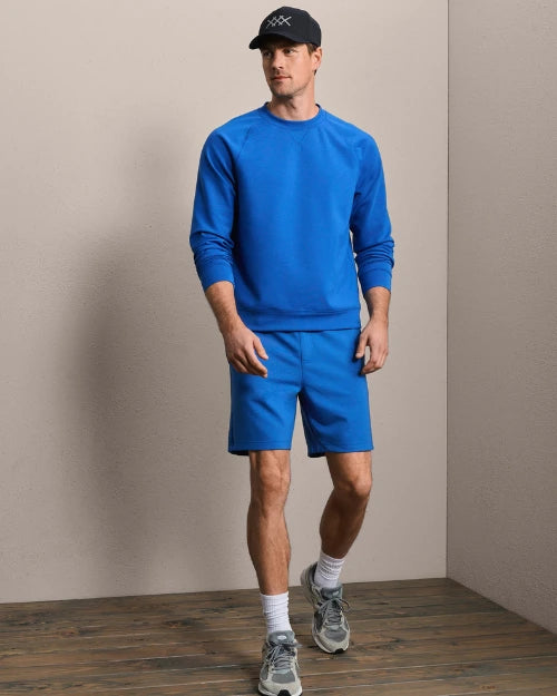 Royal blue crewneck sweatshirt and athletic shorts set with black baseball cap and running shoes