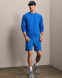 Royal blue crewneck sweatshirt and athletic shorts set with black baseball cap and running shoes