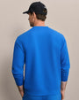 Back view of royal blue crewneck sweatshirt with raglan sleeves, styled with matching athletic bottoms and black baseball cap