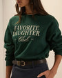 Dark green graphic sweatshirt with “Favorite Daughter Club” white typography, styled with navy pinstripe trousers and a black leather belt.