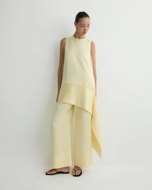 Light yellow asymmetrical sleeveless tunic top with matching wide-leg pants and black sandals