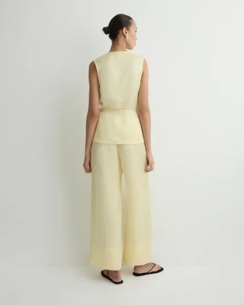 Back view of a light yellow sleeveless wrap top with matching wide-leg cropped pants and black sandals
