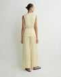 Back view of a light yellow sleeveless wrap top with matching wide-leg cropped pants and black sandals