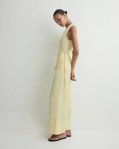 Side view of a light yellow sleeveless wrap top with tie waist and matching wide-leg cropped pants
