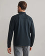 Back view of a black textured quarter-zip performance pullover with long sleeves, mock neck collar, breathable athletic fabric, and athletic fit paired with gray pants.