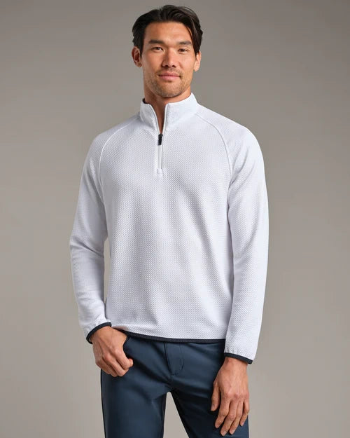 Person wearing a white textured quarter-zip performance pullover with long sleeves and navy pants against a neutral studio background.