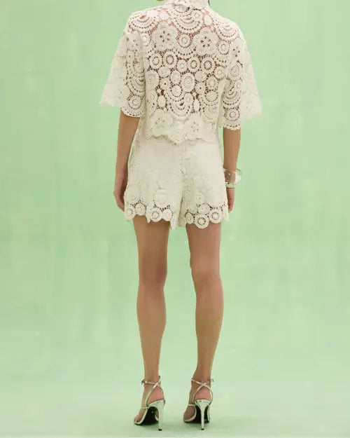 Back view of women's white crochet lace blouse and matching lace shorts set featuring floral crochet detailing, scalloped hems, and an elegant summer resort wear design.