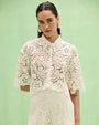 Women's white crochet lace blouse with floral pattern, tie-neck collar, elbow-length sleeves, and coordinating lace shorts.