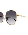 Close-up of round-framed sunglasses with a thin gold metal frame with grey lenses. The sunglasses have black earpieces and decorative small diamonds.