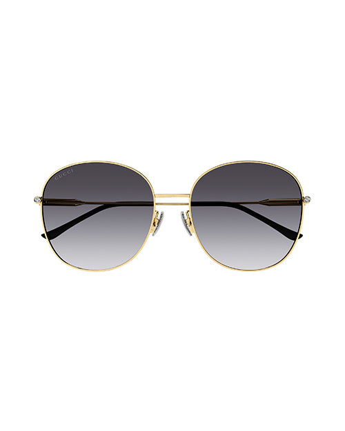 Front view of round-framed sunglasses with a thin gold metal frame with grey lenses. The sunglasses have black earpieces.