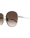 Close-up of round-framed sunglasses with a thin silver metal frame with brown lenses. The sunglasses have tortoiseshell colored earpieces and small gold accents.