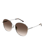 Round-framed sunglasses with a thin silver metal frame with brown lenses. The sunglasses have tortoiseshell colored earpieces and gold accents.