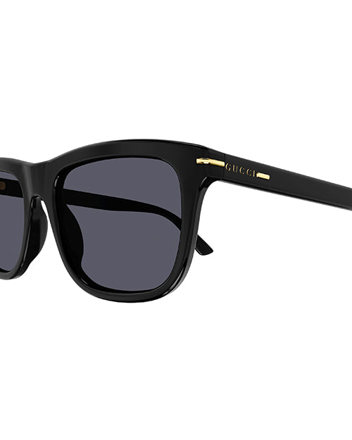 Close-up of classic black wayfarer sunglasses with thick frames, featuring gold lettering of the brand name on the temples. The lenses are black.