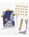 Stationery set with a blue notecard featuring a golden butterfly and abstract swirls, gold pen, sticker sheet with butterfly designs, and an envelope.