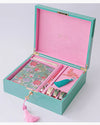 A decorative stationery set in a turquoise and pink box. Includes a floral notebook, pen, tassels, washi tape, and bird illustration, conveying elegance.