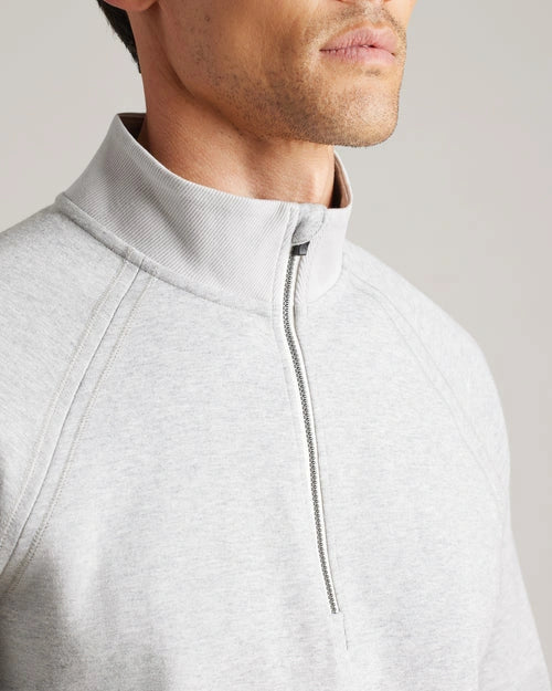 Close-up of a light gray quarter-zip pullover featuring a mock neck collar, quarter-zip closure, raglan seams, and soft knit fabric.