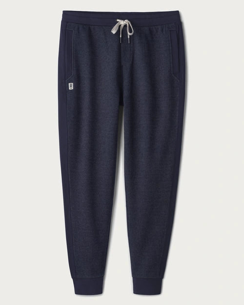 Navy jogger sweatpants with an elastic waistband, adjustable drawstring, side pockets, tapered legs, and ribbed cuffs displayed on a light gray background.