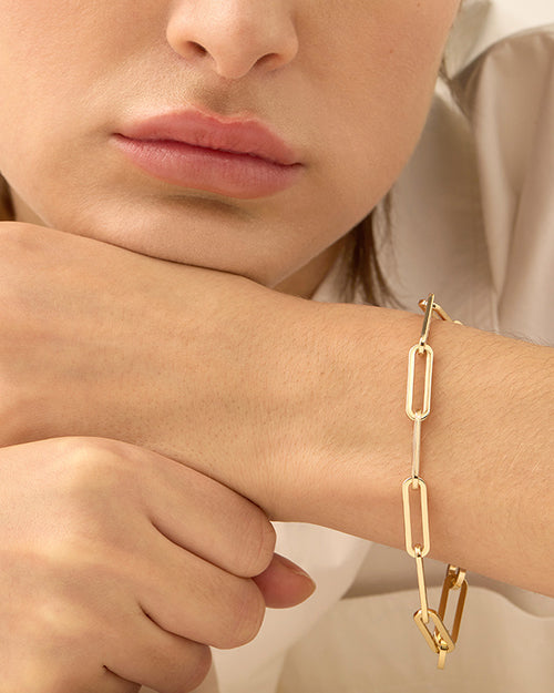 A gold-tone bracelet with elongated chain links of uniform size modeled on a wrist.