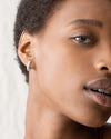 Close up on model's side face wearing teeni toni huggie earrings.