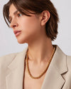 Head shot of a woman with a gold braided necklace around her neck