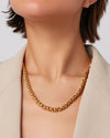 Zoomed in image of a woman's neck wearing a gold braided necklace. 
