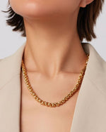 Zoomed in image of a woman's neck wearing a gold braided necklace. 
