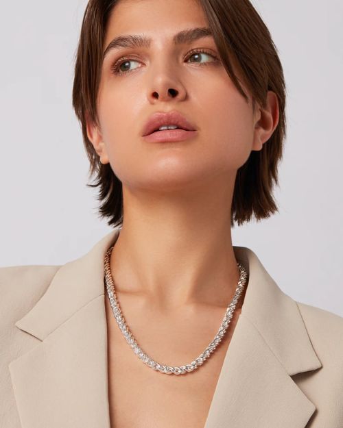 Head shot of a woman wearing a silver braided chain necklace