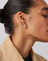 A woman's right-side profile of her ear focusing on the silver small double stacked hoop earrings she is wearing. 