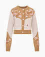 Product image of a cropped tan and cream button-front knit cardigan with star, floral, and horseshoe motifs, ribbed trim, and long sleeves.