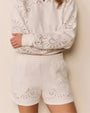 A white cropped sweatshirt and matching shorts, both featuring eyelet-style cutout patterns