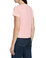 Back view of a person wearing a light pink graphic T-shirt with dark pinstriped jeans on a plain background.