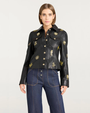 Woman with a black jacket with gold embellishments against a white background.
