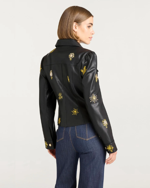 Woman with a black jacket with gold embellishments against a white background.